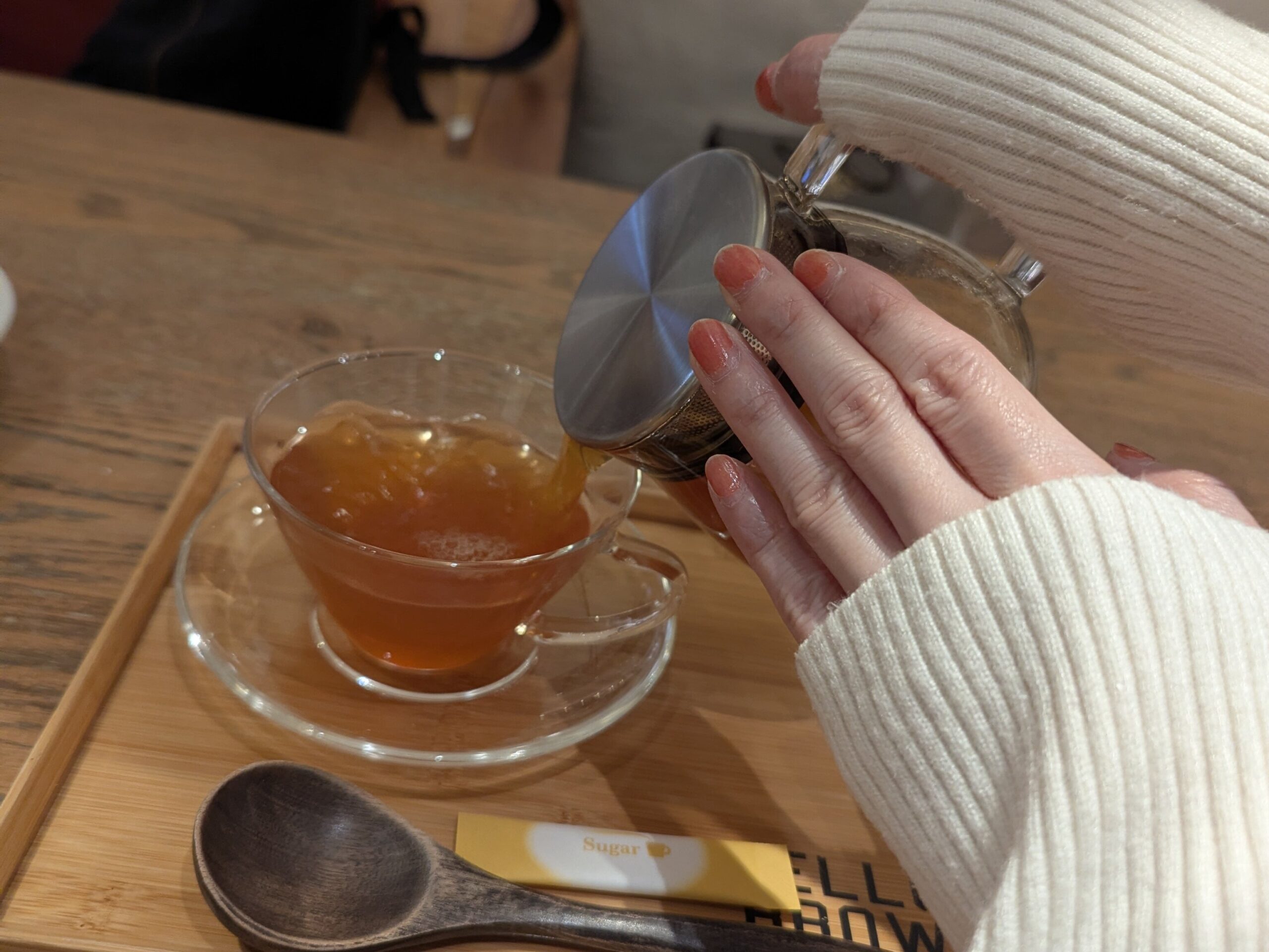 ガラスのティーポットからカップに紅茶を注ぐ手元